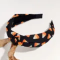 Closeup of Halloween candy corn printed knotted headband with black fabric and unique twist. - Orange Triangle