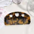 Detail view of the tortoiseshell acetate hair comb featuring cute heart cutouts for daily styling. - Yellow and Black Leopard