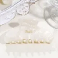 Close-up detail of French acetate hair claw clip, milky crescent design with gold stamp. - Medium Crescent - Pearlescent White