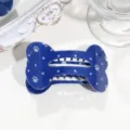 Blaue knochenformige Haarklammer mit weissen Sternen und Pfotenabdruecken, Detailansicht Accessoire. - Pfote Stern Knochen Haarklammer