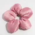 Nahaufnahme Detail eines rosa Satin Blumen Haargummis, weiche Textur und niedliches Design. - Pfirsich