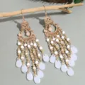 Detailed shot of long gold-tone tassel earrings featuring delicate white beads and teardrop drops. - White Rice Bead Earrings