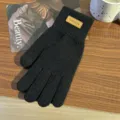 Primo piano di un guanto touchscreen in maglia nera con etichetta in pelle su tavolo di legno. - Etichetta Orizzontale Dita Separate / Nero