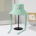 Green and white gingham bucket hat detail, showcasing the front label and long chin straps. - Plaid Double Sided Bucket Hat / Green
