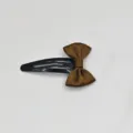 Detail view of the brown ribbon bow on a black metal snap hair clip close up shot. - Coffee