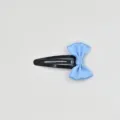 Detailed shot of a cute light blue ribbon bow attached to a black metal snap hair clip. - Blue Gold