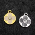 Détail en gros plan de pendentifs trèfle en métal avec strass au centre, dorés et argentés. - Fleur