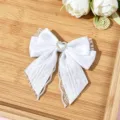Close-up detail of white lace bow hair clip featuring a sparkling rhinestone heart accent. - White