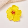 Dettaglio in primo piano di un fermaglio per capelli con fiore di ibisco giallo brillante. - Giallo brillante