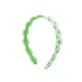 Detailed close-up of a sweet green headband decorated with lovely white daisy flowers. - Green