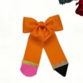 Close-up detail of a creative pencil shaped hair bow accessory, featuring vibrant orange ribbon. - Orange