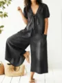 Detail view of stylish dark wash denim jumpsuit featuring v-neck and wide leg silhouette. - S / Black