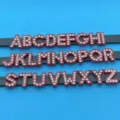 Vue de detail rapprochee de lettres alphabetiques en strass rouge sur laniere, ideal pour DIY. - Lettre A / Rouge