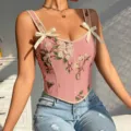 Detalle cercano de corsé floral rosa para mujer con bonitos lazos en hombros y escote V. - Rosa