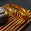 Detailed view of a golden amber synthetic beeswax bangle bracelet showcasing natural swirl patterns. - Flat Small / Golden Amber