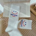 White ribbed mid-tube socks featuring cute smiley face and letter print design for daily wear. - One Size 34-39 / White