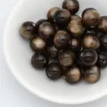 Gros plan détaillé de perles en résine œil-de-chat marron foncé dans un bol blanc pour DIY. - 8mm / Marron