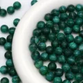 Primo piano di perline rotonde glitterate verde scuro, ideali per dettagli di gioielli fai da te. - 10mm / Motivo legno di sicomoro