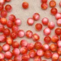 Primo piano dettagliato di perline tonde in resina rossa occhio di gatto, ideale per gioielli DIY. - 10 mm (diametro del foro circa 1,8 mm) / Rosso arancio giada