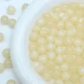 Primer plano detallado de cuentas de resina amarillo claro estrelladas para joyeria DIY. - 8mm / Blanco Roto