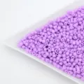 Close up of purple seed barrel beads in a white sorting tray for DIY handmade jewelry making. - Pink Purple