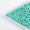 Close-up detail view of cyan glass seed beads neatly arranged in a white sorting tray. - Cyan
