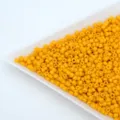 Close-up detail of yellow glass seed beads, solid barrel beads for DIY handmade jewelry bracelets. - Orange