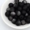 Gros plan détail de perles œil de chat mates noires dans un bol blanc pour bijoux DIY. - 8mm / Noir mat
