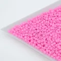 Close-up detail shot of pink solid barrel seed beads for DIY handmade jewelry bracelets. - Pink