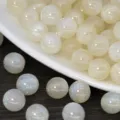 Close-up detail of shimmering resin glitter beads, mermaid loose beads for DIY handmade jewelry. - Beige