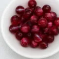 Close-up detail of deep red cat-eye beads in a white bowl, perfect for DIY jewelry making. - 11. Dreamy Wine Red