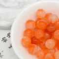 Close-up detail of orange marbled acrylic beads in a white bowl, perfect for DIY jewelry crafts. - 7. Orange Charm
