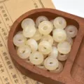 Vista dettagliata di perline di resina glitterate in vassoio di legno per accessori fai da te. - Bianco avorio