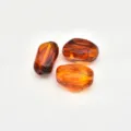 Close-up of irregular stained acrylic amber imitation beads with drilling holes for DIY jewelry. - Amber