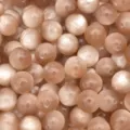 Close-up detail of champagne resin cat-eye beads, showing chatoyancy luster and drill holes. - Brown