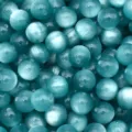 Close-up detail of blue cat eye resin beads, smooth round DIY craft supplies for bracelets. - Winter Blue
