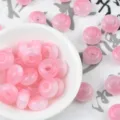 Close-up detail of pink resin cat eye wheel beads, perfect for DIY jewelry crafting accessories. - Pink
