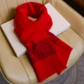 Detailopname van een helderrode wintershawl met een klassiek geometrisch randpatroon. - Universele vernieuwing