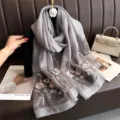 Gedetailleerd overzicht van prachtige bloemborduursels op een elegante grijze sjaal. - Grijs