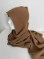 Gedetailleerd overzicht van de bruine capuchonsjaal, getextureerde katoenen stof met mooie drape. - Bruin