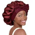 Detail view of a luxurious burgundy satin sleep bonnet featuring a stylish bow and wide band. - 58cm Head Circumference (One Size) / Dark Red