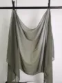 Close-up detail of a lightweight olive green chiffon scarf hanging on display. Soft fabric texture. - Camel
