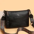 Borsa a tracolla da donna nera in pelle con ampia tracolla etnica e logo elegante. - Nero