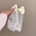 Detailaufnahme der cremefarbenen Satin-Schleifen-Haarspange mit weißem Spitzenschleier für Damen. - Gelbe Rock-Stil Haarspange