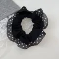 Close up of black polka dot hair scrunchie with sheer lace ruffle edge, cute daily accessory. - Black