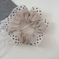 Detailed view of cream polka dot scrunchie with lace trim, sweet forest style hair accessory. - Khaki