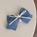 Detailed shot of the blue denim bow hair clip with white ribbon and pearl pendant. - Pearl Butterfly Hair Clip