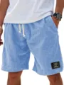 Close-up detail of men's casual light blue linen shorts with drawstring and black label. - S / Sky Blue