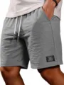 Vista ravvicinata dettagliata di pantaloncini casual da uomo grigi con coulisse bianca. - Taglia S / Grigio