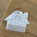 Detalle del portatarjetas de identificación con forma de casa y diseño de cuadros. - Casa Lazo / Tostado